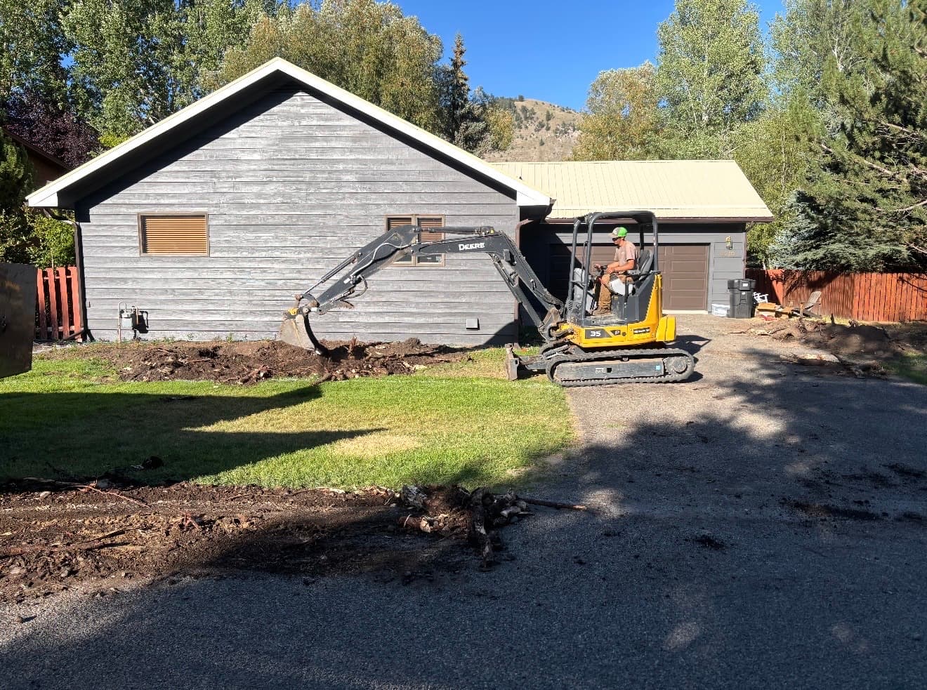 Mini excavator digging alongside a Jackson home for a landscape install